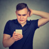 confused man looking at his phone